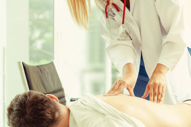 woman doctor and male patient in hospital office - physical injury backache occupation office imagens e fotografias de stock