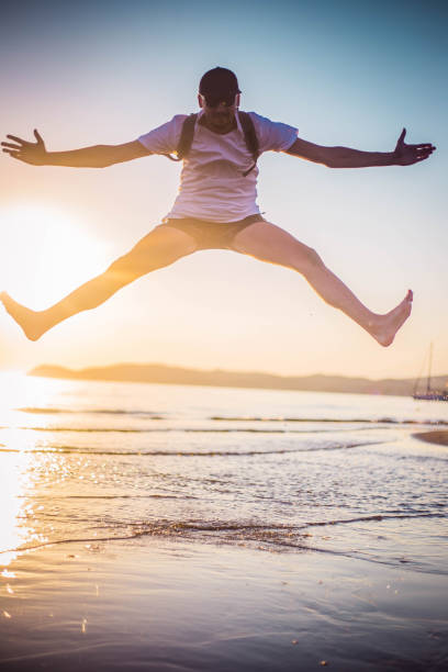 istock Happy young man jumping at the beach 1037184296