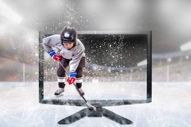 Junior ice hockey player in competitive sports gear standing inside brightly lit outdoor stadium on TV monitor. Concept of realistic Live 3D TV or Virtual Reality sports. Fictitious stadium was created in Photoshop and monitor was shot separately and then composited together with the model.  Model release and reference images attached.