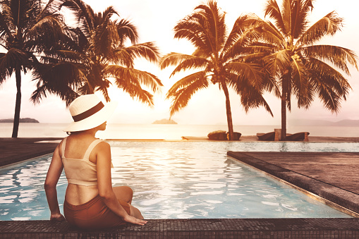 Carefree woman relaxation in swimming pool summer sunset Holiday concept