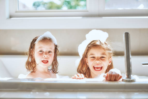 children are bathing in a bath Happy children girls are bathing in a bath with foam and bubbles. taking a bath photos stock pictures, royalty-free photos & images