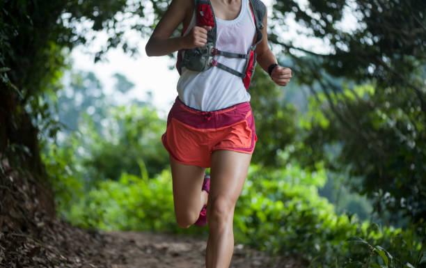 istock Young woman trail runner running on tropical forest trail 1037291208