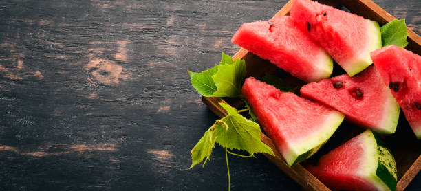 watermelon in a wooden box. sliced to pieces of watermelon. on a wooden background. free space for text. top view. - n64 imagens e fotografias de stock