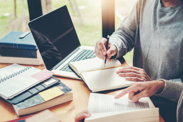 istock High school or college students studying and reading together in library 1037295952