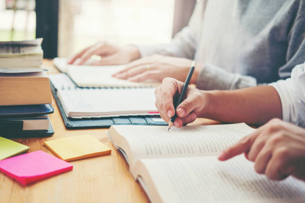 istock High school or college students studying and reading together in library 1037296030