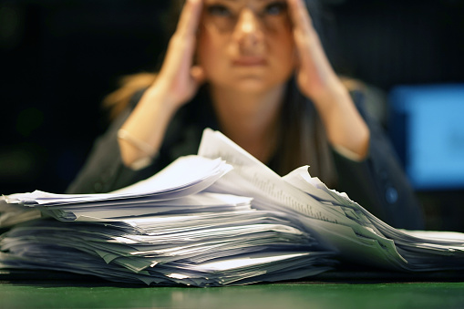 Close-up of office worker is distressed with a lot of paperwork in front of her. A lot of paper work in office. Yelling and screaming for bad results. Businesswoman in problems.