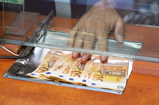 Cash money euro, at bank office or currency exchanger. Male hand with euro money in cash department window. Currency exchange concept. Clerk giving cash money to customer at bank office.