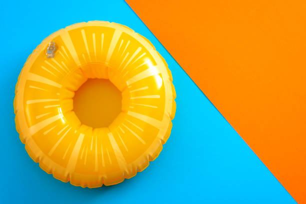 lifebuoy isolated on blue and orange background with copyspace Summer vacation and safety equipment for swimming with a life buoy isolated on an orange and blue minimalist background with copy space inflatable stock pictures, royalty-free photos & images