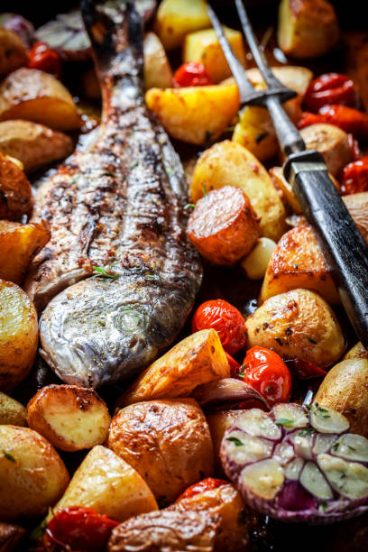 istock Roasted seabream and potatoes with herbs and tomatoes 1037361926