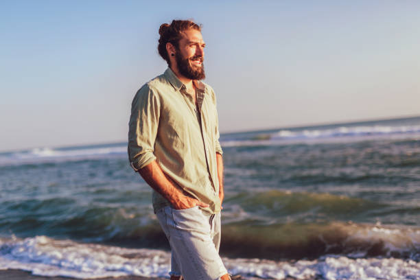istock One man walking on the beach on sunset. 1037369794