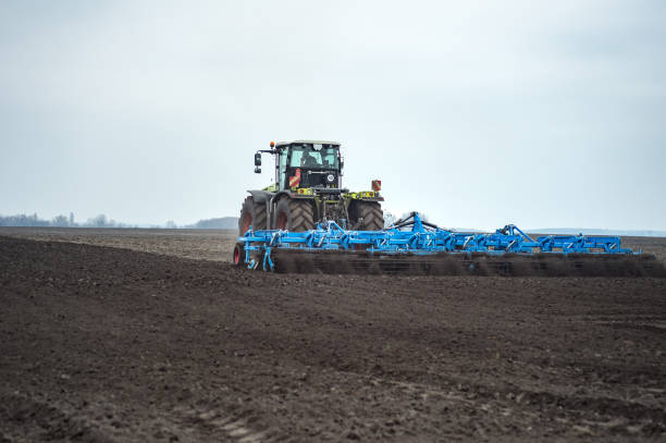istock seedbed cultivator in farmlands. Tractor plows a field. Agricultural work in processing, cultivation of land. Farmers preparing land and fertilizing. 1037370416