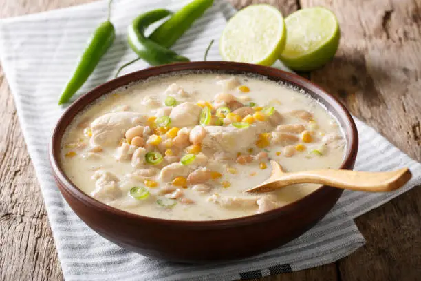 Photo of Homemade white chili chicken with beans, lime and corn close-up. horizontal