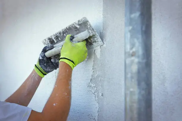 Plasterer making new white plaster with a trowel