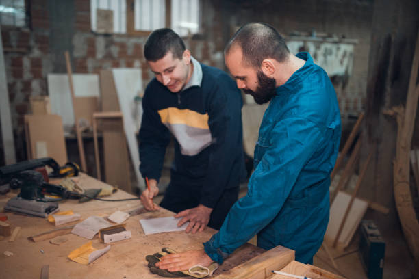 istock Two people working in the carpenters workshop and making wooden objects 1037391440