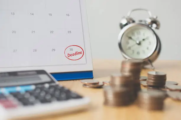 Photo of Tax payment season and finance debt collection deadline concept. Money coins stack, calendar, calculator and clock