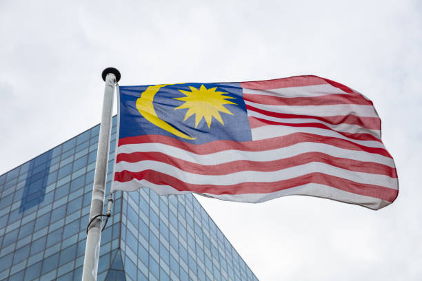 istock Malaysia flag on a pole waving, modern office building background 1037404578