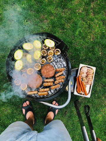 first person perspective photo of a male preparing barbecue in his backyard // mobilestock photo