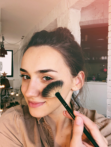 Young woman taking a selfie and creating a DIY make up tutorial