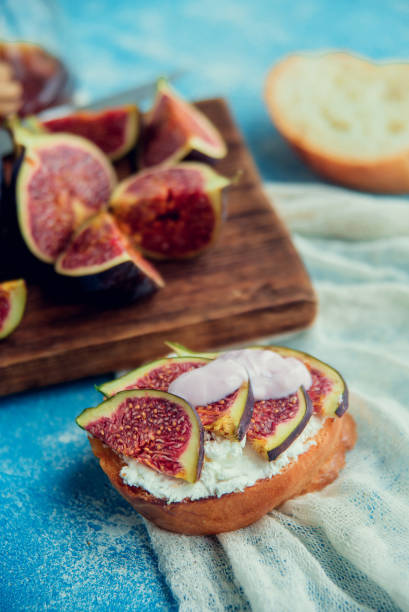 istock Autumn dessert: bruschetta with ripe figs, soft cheese and honey on a light background. 1037449532