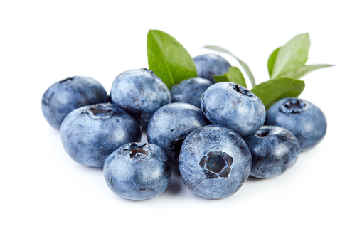 heap of fresh ripe blueberry fruits with green leaves isolated on white background