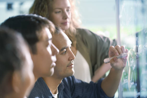 istock Group of businesspersons discussing work and using glass board in the office 1037483456