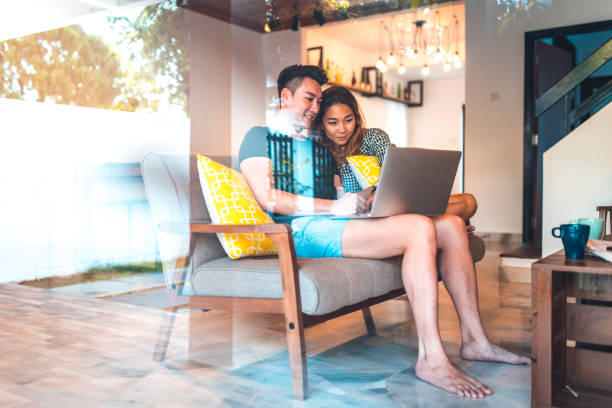 istock Young couple using laptop on sofa in living room 1037487392
