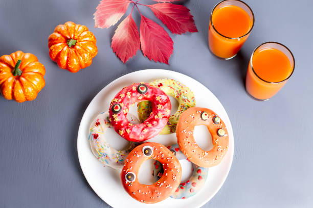 Halloween donuts with pumpkin juice and autumn leaves.