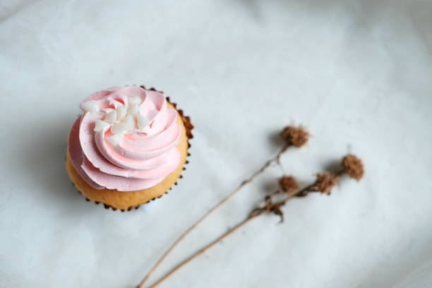 istock Cupcake and dry Marguerite Daisy flowers on white Tablecloth. Copy Space 1037493196