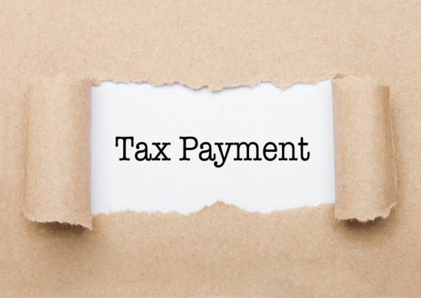 istock Tax Payment text appearing behind torn brown paper 1037513676