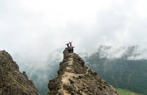 group of young male and female university students on top of a sharp mountain peak in the Dolomites of Alta Badia in Italy