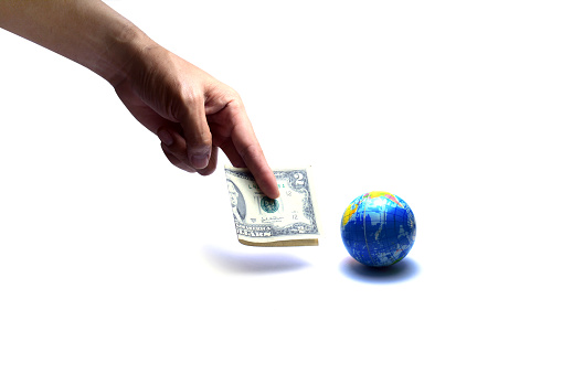 buy the world with some money .the hand showing two dollar note  near  the blue globe on white background isolated