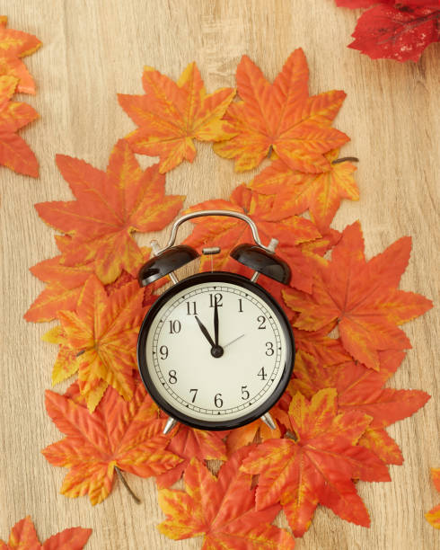 istock Autumn Black vintage clock with dried maple leaves on wooden 1037540328