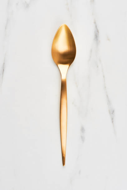istock Golden spoon on white marble background 1037550028
