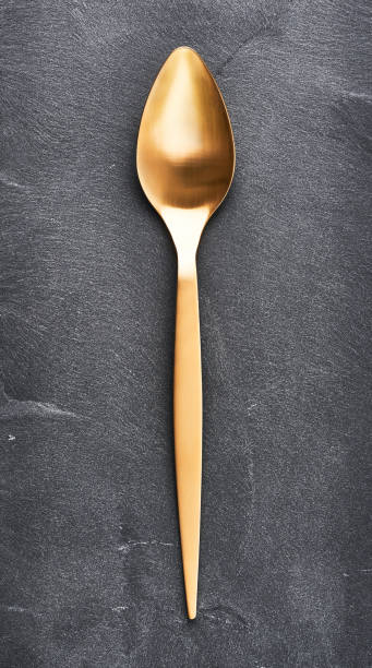 istock Golden spoon on black stone background 1037550032