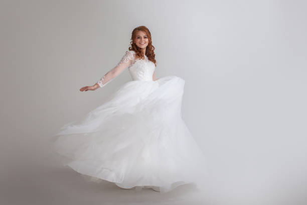 istock Dancing young woman in wedding dress. Charming bride on Light background. 1037567242