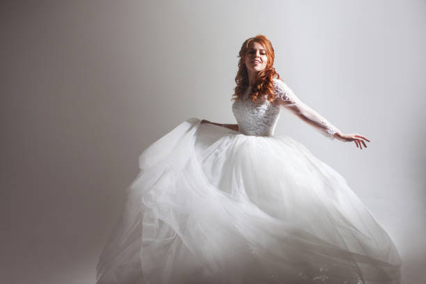 istock Dancing young woman in wedding dress. Charming bride on Light background with a shadow 1037567356