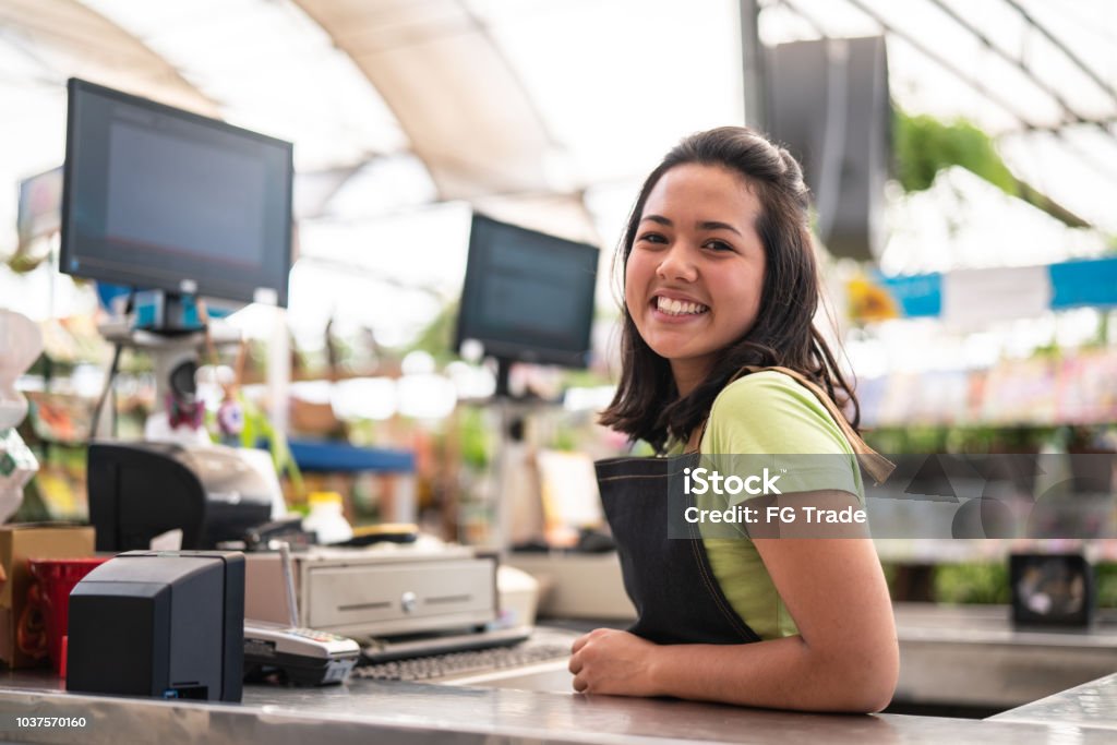 Portrait of confident owner leaning on checkout counter at flower shop Flower Shop Supermarket Stock Photo