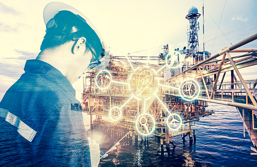 Double exposure of Engineer or Technician man with digital icon operated platform or plant by using tablet with offshore oil and gas platform background for industry business concept.