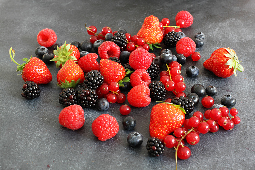 Choice of fresh berries on dark board, high angle view