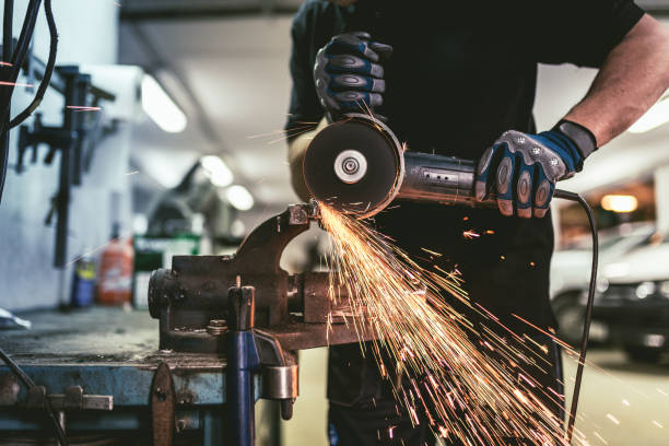 operaio dell'industria pesante che taglia l'acciaio con una smerigliatrice ad angolo. - welding metal manufacturing industry foto e immagini stock