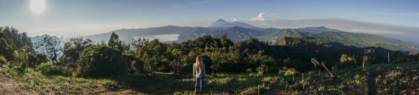 panoramiczny widok na wędrówki young woman kontempluje wulkaniczny krajobraz ze szczytu wzgórza, patrząc na wulkany bromo- ludzie podróżują przygoda koncepcji - bromo crater zdjęcia i obrazy z banku zdjęć