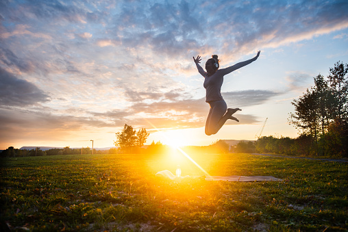 Jumping on exercising mat at sunset.