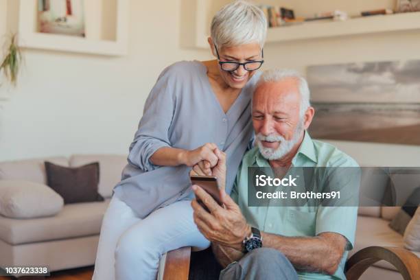 Senior Par Mediante Teléfono Móvil Foto de stock y más banco de imágenes de Tercera edad - Tercera edad, Teléfono móvil, Pareja mayor