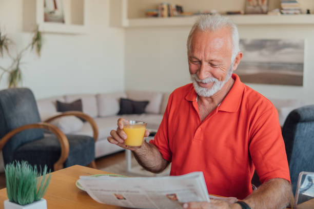 istock Old man reading newspapers and drinking orange juice 1037623362