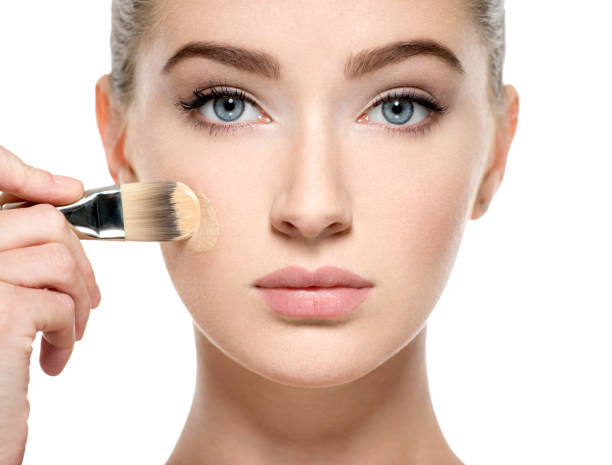 istock Girl applies  tonal foundation on face use makeup brush 1037626322