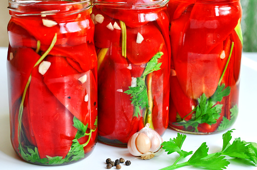 Jars of pickled vegetables: organic red pepper and green parsley. Marinated and canned food.