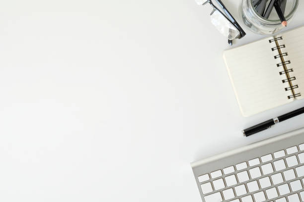 istock Topview office desk keyboard computer and glasses with notebook paper on white table with copy space. 1037634406