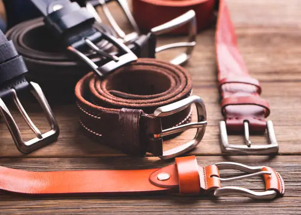 Photo of Collection of leather belts on a wooden table