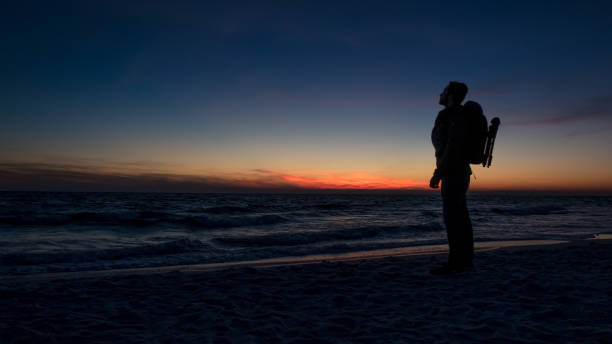 istock Guy stands in front of dramatic sunset over the ocean 1037634652