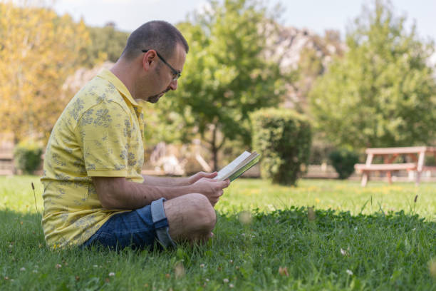 istock Mid adult  man reading a book in park 1037644292